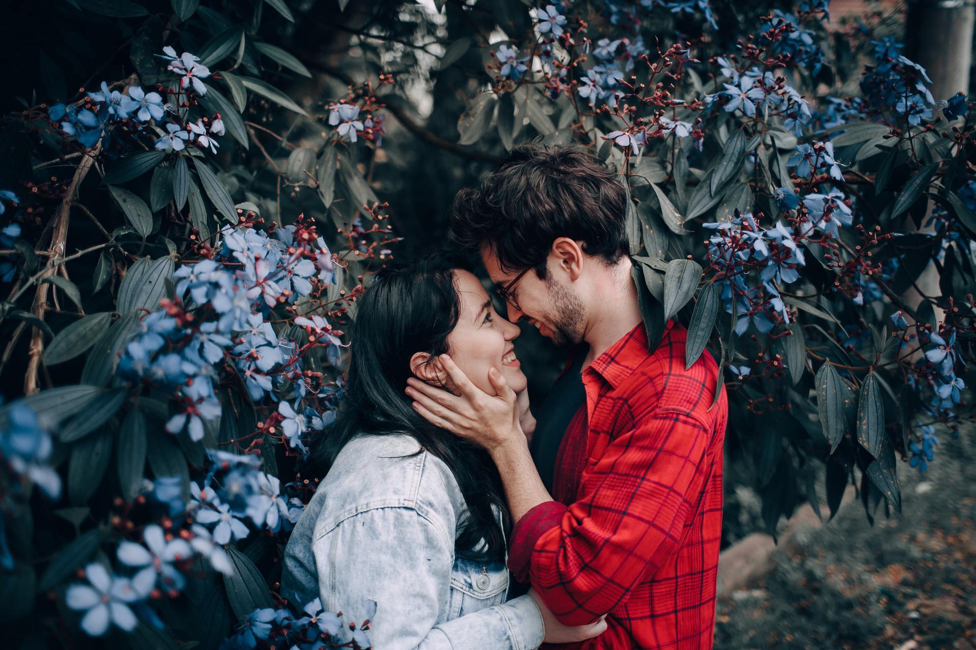 man-holding-woman-s-face-beside-blue-cluster-flowering-plant-2055232.jpg